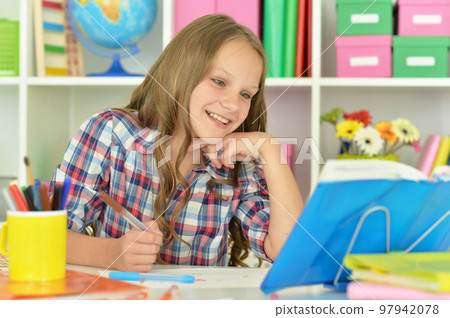little girl studying at home at the table little girl studying at home at the table 97942078