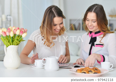 two emotional female friends posing at desk two emotional female friends posing at desk 97942118