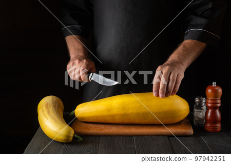 The cook cuts ripe yellow marrow with a knife. Fried zucchini is a great diet for breakfast or lunch. Work environment on the kitchen table of the restaurant. Free advertising space 97942251