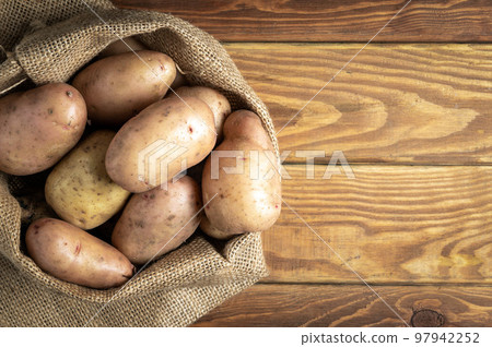 Sack of potatoes after harvest on vintage wooden planks. Organic potato for cooking. Free advertising space 97942252