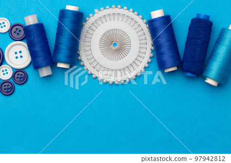 Thread spools and buttons on blue abckground 97942812