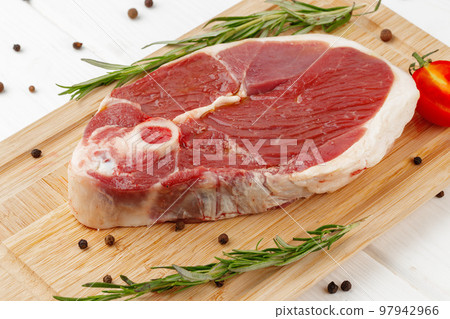 Raw lamb steak on board on white wooden table 97942966