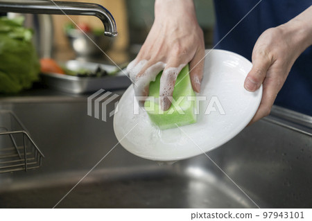 Young man's hand washing dishes 97943101