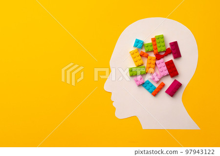 Papercut head silhouette with toy constructor pieces on yellow background 97943122