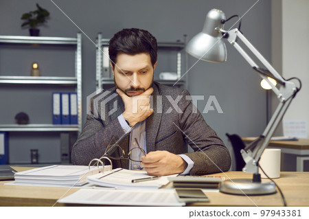 Young businessman, auditor or financial accountant doing paperwork in the office Young businessman, auditor or financial accountant doing paperwork in the office 97943381