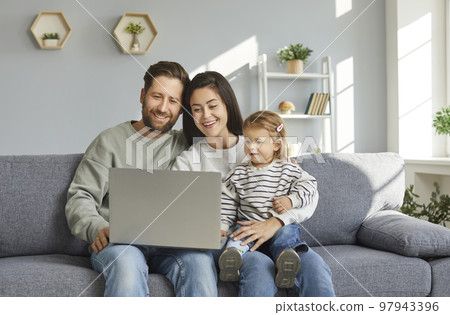 Happy family chatting online using laptop while sitting at home Happy family chatting online using laptop while sitting at home 97943396