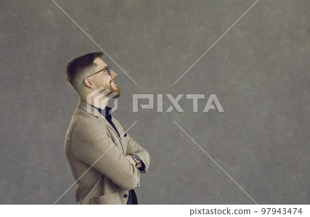 Side view of a happy young businessman looking at copy space on a grey background Side view of a happy young businessman looking at copy space on a grey background 97943474
