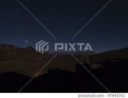 Long exposure night shot of Roques de Garcia with La Catedral volcanic rock formation at El Teide national park, night winter sky with stars on dark blue. Tenerife Canary islands, Spain 97943701
