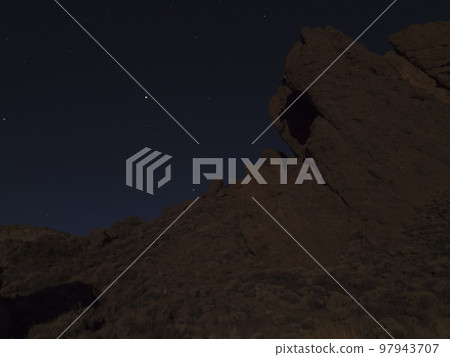 Long exposure night shot of Roques de Garcia volcanic rock formation at El Teide national park, night winter sky with stars on dark blue. Tenerife Canary islands, Spain 97943707