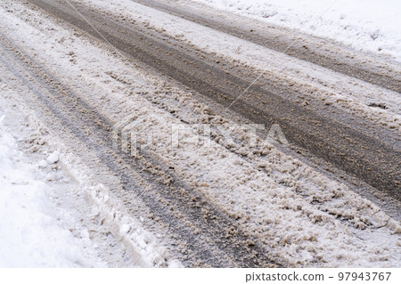 De-icing chemicals and sand on the snowy winter road De-icing chemicals and sand on the snowy winter road 97943767