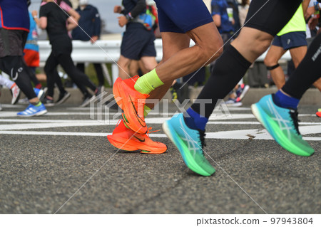 City marathon: the feet of a marathon runner running up a slope 97943804