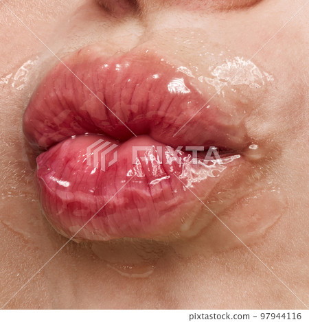 Kiss. Closeup of beautiful sensual woman's lips covered with honey, transparent gel. Beauty, fashion, style concept. Emotions and feelings 97944116