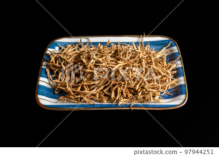 Japanese honeysuckle dried herbs - latin name Lonicera japonica - on a plate isolated on black Japanese honeysuckle dried herbs - latin name Lonicera japonica - on a plate isolated on black 97944251