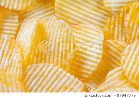 Yellow crispy ridged potato chips close up. Food background 97947579