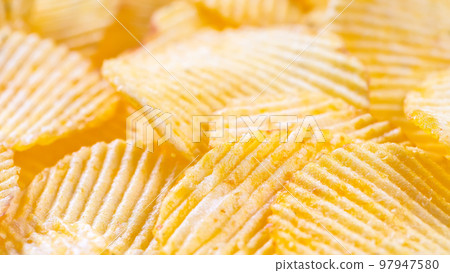 Yellow crispy ridged potato chips close up. Food background Yellow crispy ridged potato chips close up. Food background 97947580