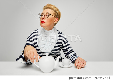 Extravagant, stylish and fashionable mature woman posing isolated over grey studio background. Fashion, style, beauty and emotions concept 97947641