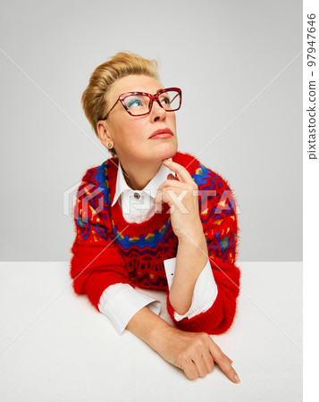 Extravagant, stylish and fashionable mature woman posing isolated over grey studio background. Fashion, style, beauty and emotions concept Extravagant, stylish and fashionable mature woman posing isolated over grey studio background. Fashion, style, beauty and emotions concept 97947646