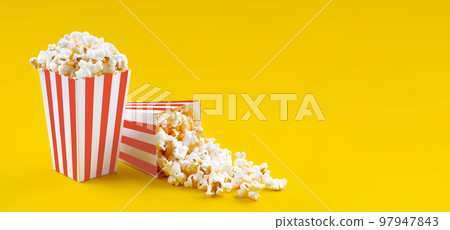 Two red white striped carton buckets with tasty cheese popcorn, isolated on yellow background 97947843