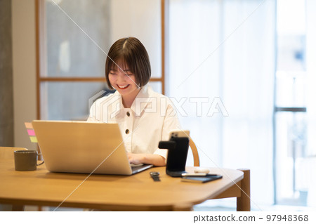 一名年輕女子在她的房間裡操作筆記本電腦 97948368