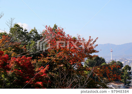 View of Kyoto Tower through autumn leaves from Kiyomizu-dera, Kyoto 97948384