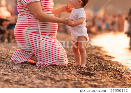 Motherhood and pregnancy. Beautiful young caucasian pregnant woman sitting with child at beach. Concept of maternity and parenthood. 97950152