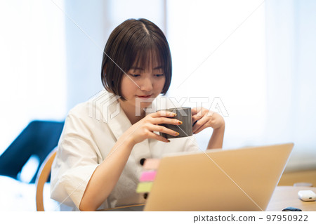 A woman taking a break while looking at her laptop A woman taking a break while looking at her laptop 97950922