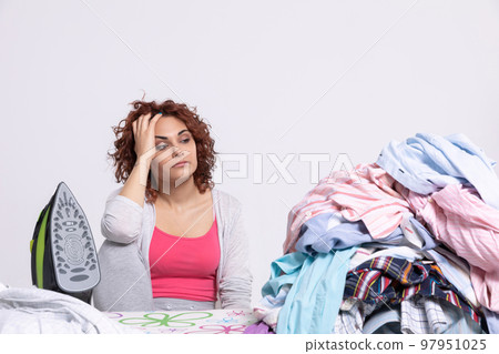 The woman can't believe she has so many men's shirts to iron this time. The woman can't believe she has so many men's shirts to iron this time. 97951025