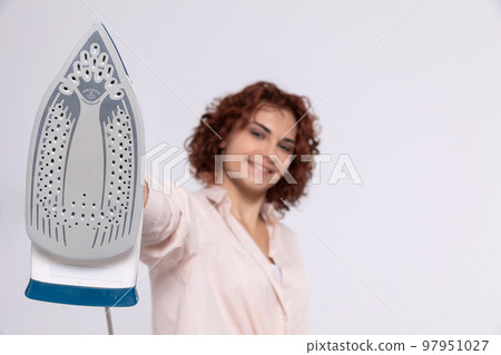The girl holds the iron on her outstretched hand right in front of her. The girl holds the iron on her outstretched hand right in front of her. 97951027