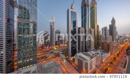 Aerial view of Dubai International Financial District with many skyscrapers night to day timelapse. 97951119