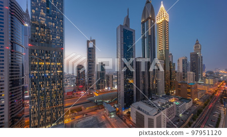Aerial view of Dubai International Financial District with many skyscrapers day to night timelapse. 97951120