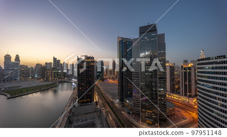 Cityscape of skyscrapers in Dubai Business Bay with water canal aerial day to night timelapse 97951148