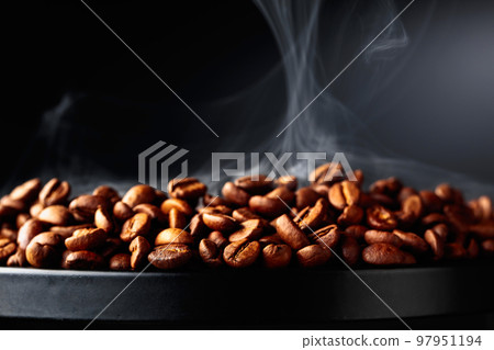 Steaming coffee beans on a black background. Steaming coffee beans on a black background. 97951194