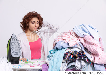 A large number of men's shirts to be ironed. The girl is resigned. A large number of men's shirts to be ironed. The girl is resigned. 97951552