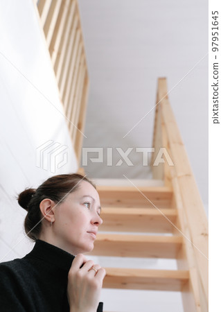 Young woman simple hairstyle against wooden stairs. Depression, loneliness and quarantine concept. Mental health, Self care, staying home. 97951645