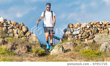 A young man practices trekking with poles A young man practices trekking with poles 97951726