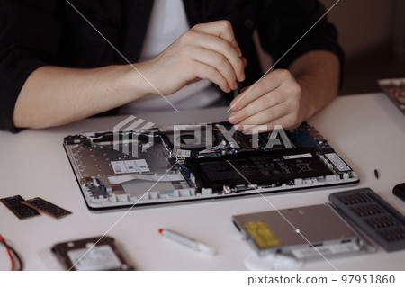Disassembling a laptop with a screwdriver in a repair shop.  97951860