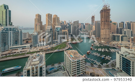 Panorama showing Dubai Marina with several boat and yachts parked in harbor and skyscrapers around canal aerial timelapse. 97953340