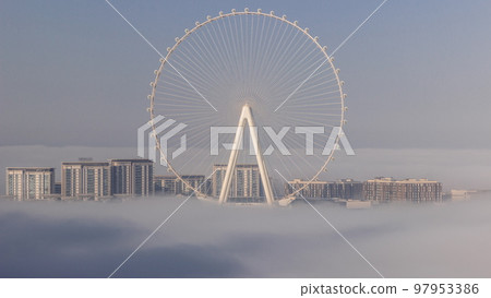 Bluewaters island with modern architecture and ferris wheel covered by morning fog aerial timelapse. Bluewaters island with modern architecture and ferris wheel covered by morning fog aerial timelapse. 97953386