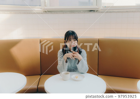 Photo of a young college girl listening to music in a cafe Photo of a young college girl listening to music in a cafe 97953925