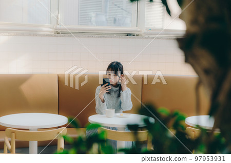 Photo of a young college girl listening to music in a cafe Photo of a young college girl listening to music in a cafe 97953931