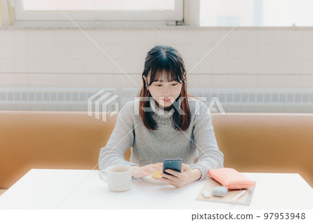 Photo of a young college girl listening to music in a cafe 97953948