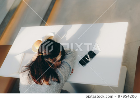 Photo of a young female college student taking a nap in a cafe 97954200