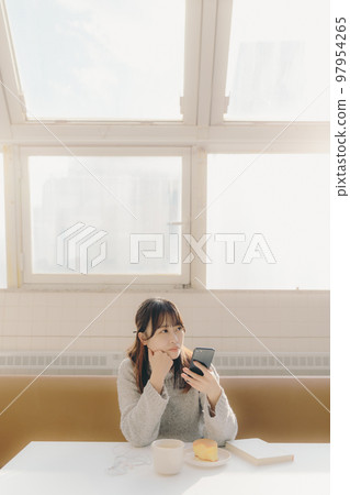 Photo of a young female college student touching a smartphone in a cafe 97954265