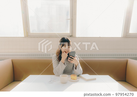 Photo of a young female college student touching a smartphone in a cafe 97954270