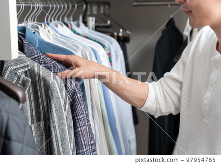 A young man choosing clothes in a walk-in closet (fashion coordination) 97954765