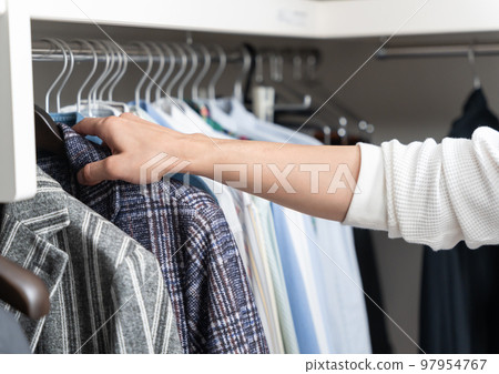 A young man choosing clothes in a walk-in closet (fashion coordination) 97954767