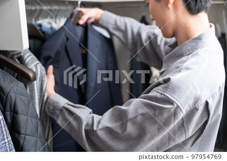 A young man choosing clothes in a walk-in closet (fashion coordination) 97954769