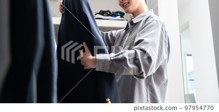 一個年輕人在步入式衣櫥裡挑選衣服（時尚搭配） 97954770