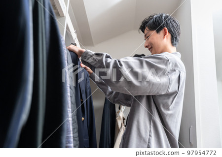 一個年輕人在步入式衣櫥裡挑選衣服（時尚搭配） 97954772