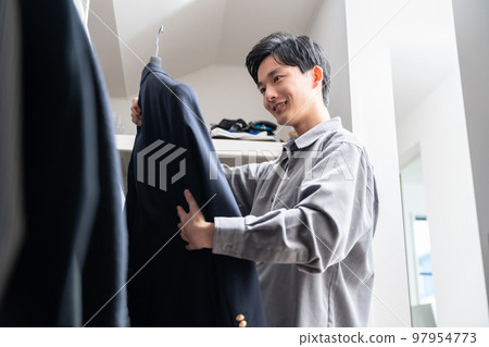 一個年輕人在步入式衣櫥裡挑選衣服（時尚搭配） 97954773